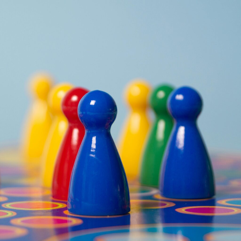 Vivid colored board game pawns arranged on a decorative game board surface.